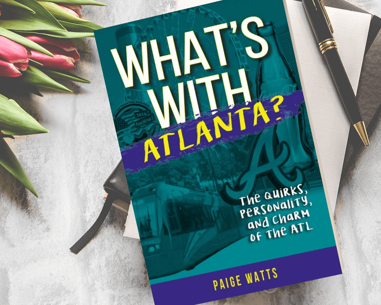 What's With Atlanta Book next to tulips and a pen